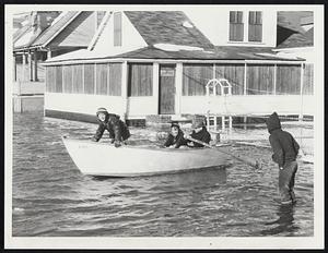 Revere Boys Frolic in MDC rowboat on Broadsound avenue where Saugus civil defense amphibious duck evacuated 40 in wake of high tides. A dozen families were forced from heatless homes, and 10 children living on the street arrived home via duck from nearby Pasteur School in Beachmont.