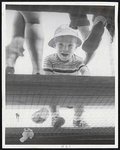 More Than Droll is Mike Schroll, 3-year-old son of Red Sox pitcher Al Schroll. Golden-haired Mike is the paperweight champion of the Red Sox children's colony at Sarasota. But here he is on the roof of the Payne Park dugout flashing that big smile that make him knockout champion everywhere.