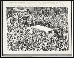 New York: A crowd of students, their hands raised in the "V' sign for peace, surround the hearse containing the body of Jeffrey Miller, of Plainview, N.Y., after funeral services at the Riverside Memorial Chapel 5/7. Miller was shot to death on the Kent State University campus 5/4.