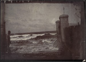 View of stormy ocean; sea wall; man on left