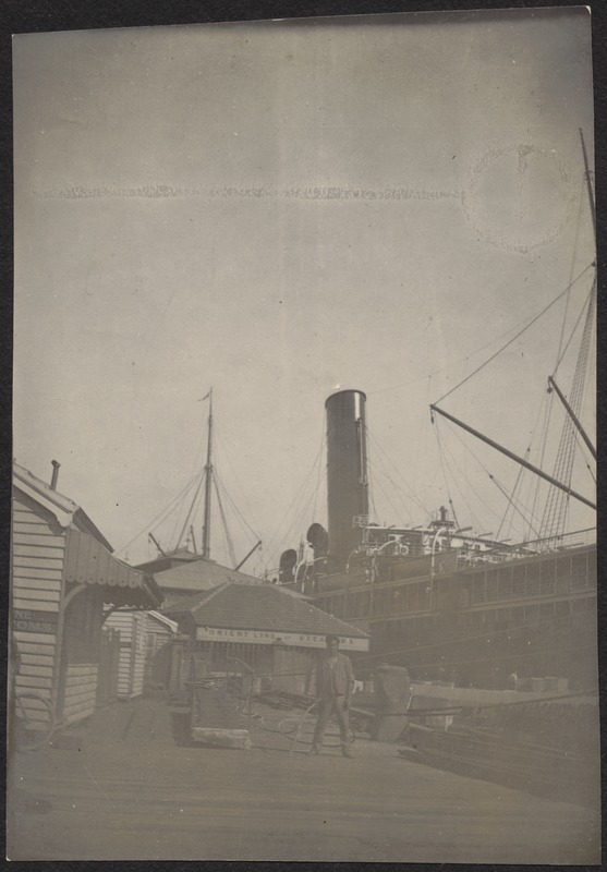 Man standing on dock, steamship behind him at dockside