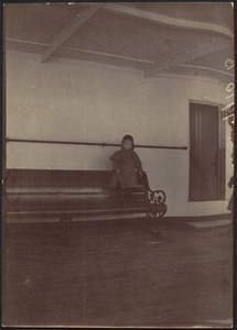 Small child standing on end of long bench on board a ship