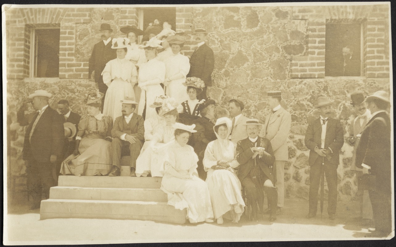 Informal group of men and women sitting and standing in front of building