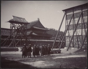 Group of Chinese soldiers (or laborers) and one western man standing in courtyard.