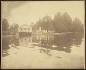 Small steamboat at dockside; building on left