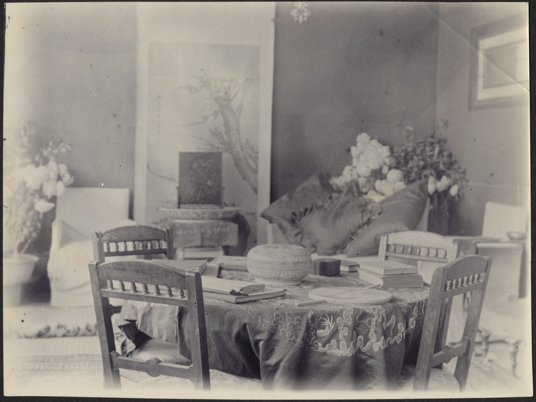 House in Peking, China — Sitting room; table with 4 wooden chairs; pillows on settee