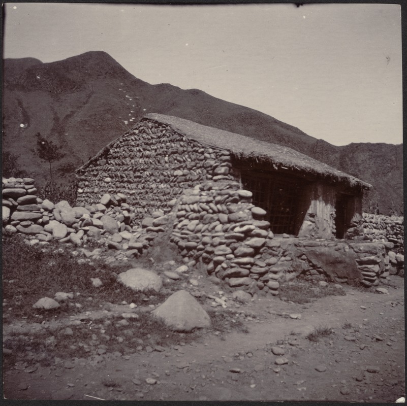 Small stone building with thatched roof in mountains