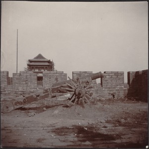 Crenelated stone structure with old cannon in foreground; building under construction in distance