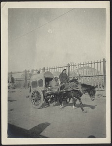 Older man in mule-drawn covered cart; man on horse riding close by