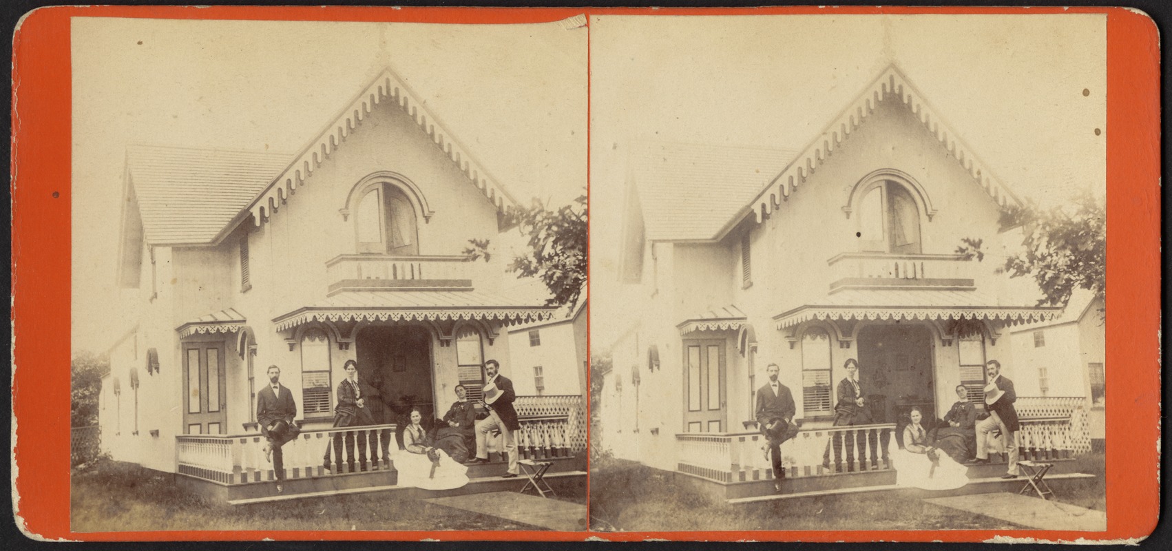 Three women and two men posing for a photograph on the porch of a cottage
