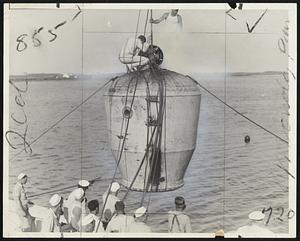 Picture shows the navy's specially constructed diving bell or rescue chamber about to be lowered from the deck of the naval tug Falcon to the submerged submarine S-4 in Great Salt Pond, off Block Island, R.I. on July 16. The ball was lowered three times and each time men from the submarine entered the bell. In 55 feet of water and were hauled in safety to the surface. The bell is connected by air and telephone lines to the submerged ship and the contact is accomplished by three men from within the bell. Escape from the submarine is by means of a hatch.