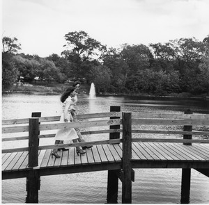 Two people walk across bridge over Bentley pond