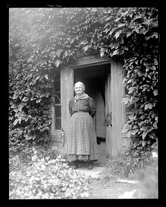 An older woman standing in front of a doorway