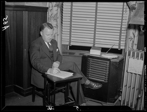 Unidentified man making notes while sitting next to radio