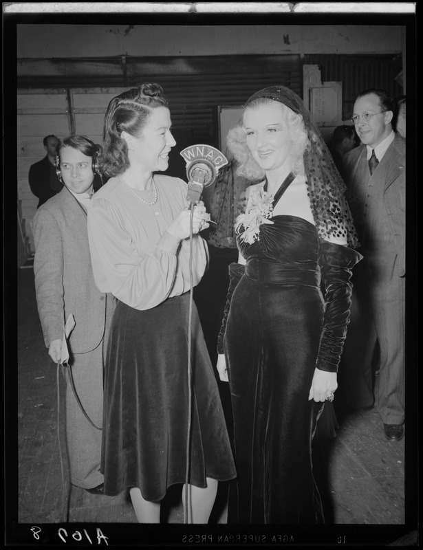 Ruth Moss of WNAC interviewing an unidentified woman in a gown backstage