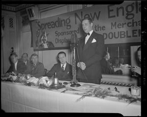 Mayor Maurice Tobin addressing Spreading New England's Fame banquet at WNAC microphone as Jim Britt, Charlie O'Rourke, and Linus Travers watch