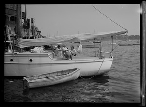 Three people on sailboat docked with a dinghy