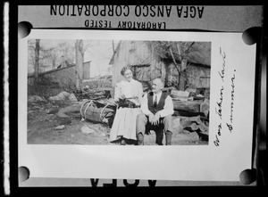 Unidentified man and woman with cat outside a barn