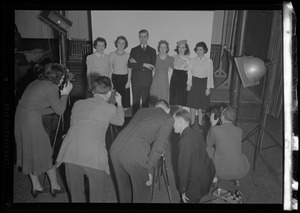 Multiple photographers taking a group portrait in a studio, possibly a photography class