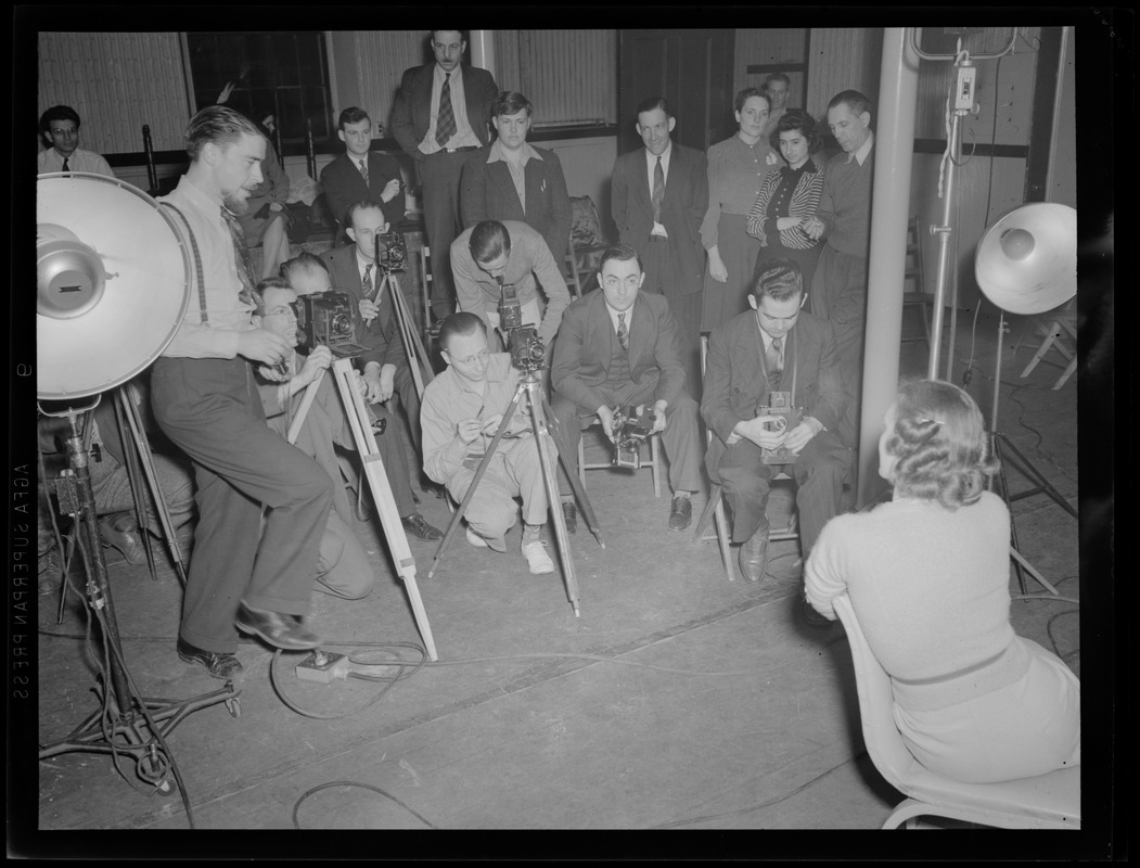 Multiple photographers taking a portrait in a studio, possibly a photography class