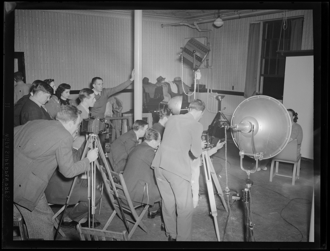 Multiple photographers taking a portrait in a studio, possibly a photography class