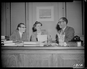 Three people sitting behind a desk