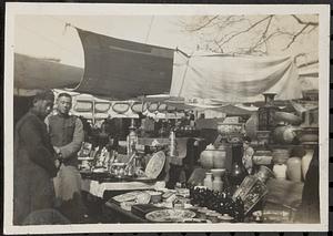 Two men standing in front of a street vendor's wares