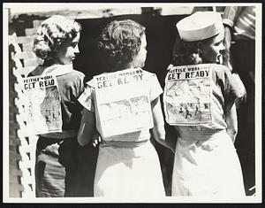 Girls Workers Aid Strike. Young women strikers in the textile mills of Gastonia, N. C., paraded with signs on their backs to aid the general strike in the industry. Photo shows three of them: left to right, Edith Fairs, Lottie Smith and Vera Mayhue.