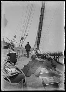 Two men sailing boat with women onboard