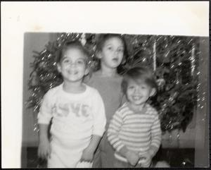 Three children in front of a Christmas tree