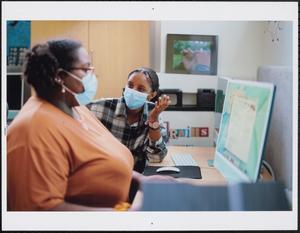 Two young women in masks at computers