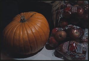 Pumpkin next to bags of apples