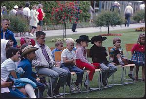 Row of children sitting on chairs watching puppet show, British Columbia