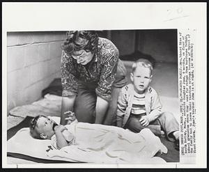 Evacuated Family -- Mrs. Edward Rice of South Hadley, Mass., comforts daughter Jane, 9 months, on floor of school gymnasium where they went for refuge from hurricane Esther. The family had to leave their vacation cottage because of threat of flood waters. Jane's brother John is at right.