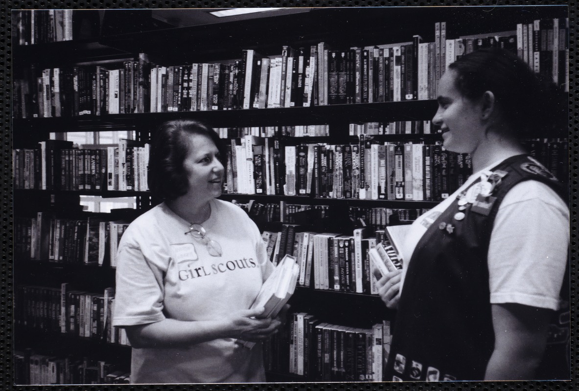 Newton Free Library, Newton, MA. Communications & Programs Office. Girl Scout leader & scout in stacks