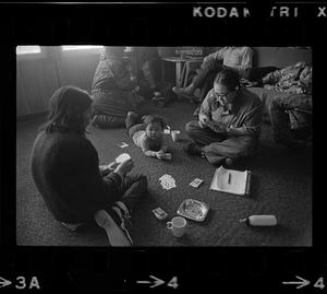 Two women play cards, group in background, Alaska