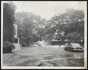 Water Deeper Than He Thought, so one motorist can be seen stalled and almost submerged on Chapel Street, Brookline, near Longwood Towers. Nevertheless, another motorist, at right, is about to attempt a passage through the flood.