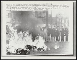 Vietnam war protesters (background) sing songs as they watch draft files burn in a small park here 9/24. The records were taken from the U.S. Selective Service Administration Offices, put in burlap bags, and carried to the park where they were burned. Fourteen persons were arrested.