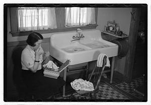 A woman sewing next to a sink full of laundry