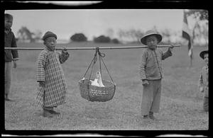 Children carrying goose in basket