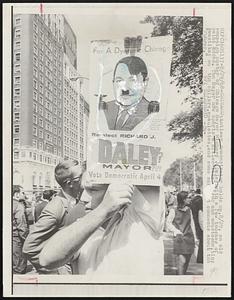 Antiwar demonstrator holds up, 8/29, an old campaign poster of Chicago Mayor Richard J. Daley, with a few touches of paint added. The Mayor now sports a Hitler-like and moustache, tiny swastikas on the collars, epaulettes, and comments about the "Fuhrer."