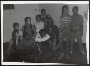 Group of teens sitting and watching a young woman standing and performing something