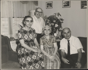 Two women and two men of Changelian family seated in front of flowers