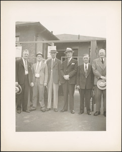 Six men standing in front of building