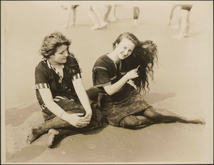 Two women on a beach, one combing her hair