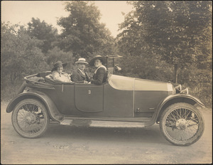 Man and two women in open two door automobile