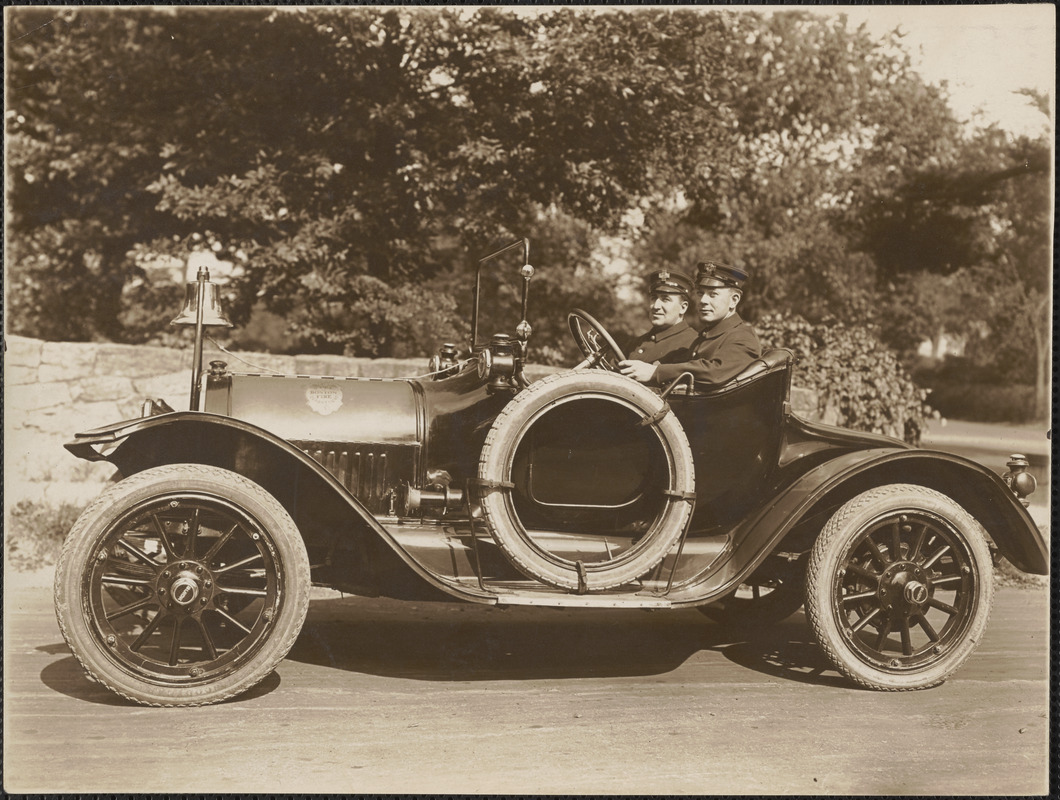 Two fire fighters driving open Boston Fire car