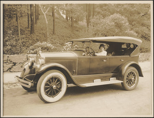Woman in closed top four door automobile, man in back seat
