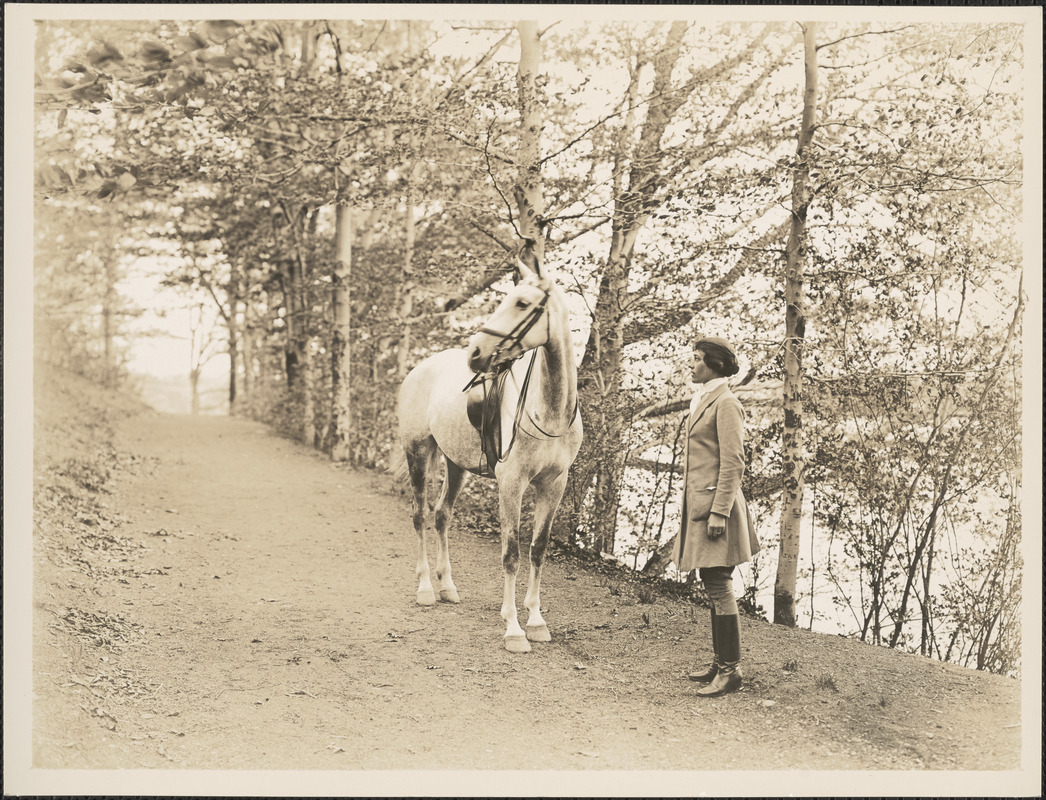 Woman standing next to a horse on path
