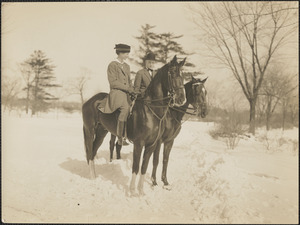 Man and woman sitting astride horses in the snow